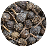 A close-up circular shot of dried Cubeb Pepper with textured, wrinkled skins and attached stems, filling the frame against a light neutral background.