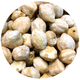 A close-up circular view of many beige Kukui Nut piled together on a white background.