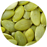 A close-up circular view of pale green pumpkin seeds filling the frame.