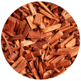 A circular close-up of small reddish-brown Sandalwood wood chips or bark pieces filling the frame, isolated on a black background.